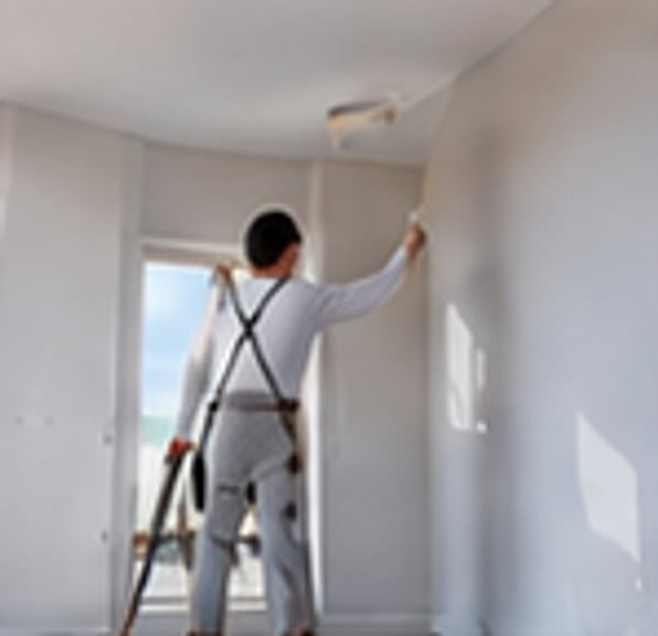 Painter rolling white paint onto an interior wall